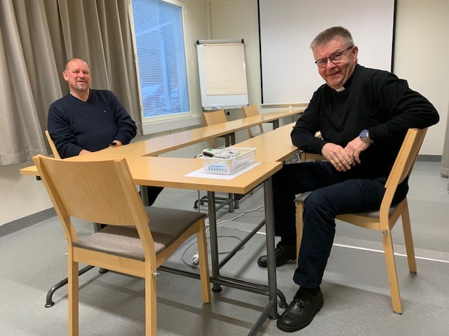 Projektipäällikkö Timo Virkki ja kirkkoherra Lauri Salminen toimistotalon kokoushuoneessa keskustelemassa.